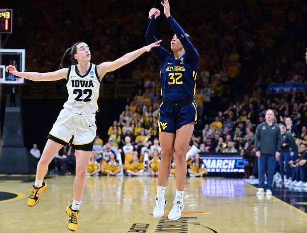 Iowa guard Caitlin Clark (22) reaches out to block a shot by West Virginia guard Kyah Watson