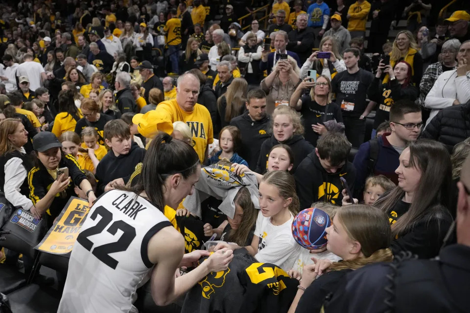 Iowa guard Caitlin Clark (22) signs autographs for fans following their 91-65 victory over Holy Cross in a first-round NCAA tournament game Saturday in Iowa City, Iowa. (AP Photo/Matthew Putney)